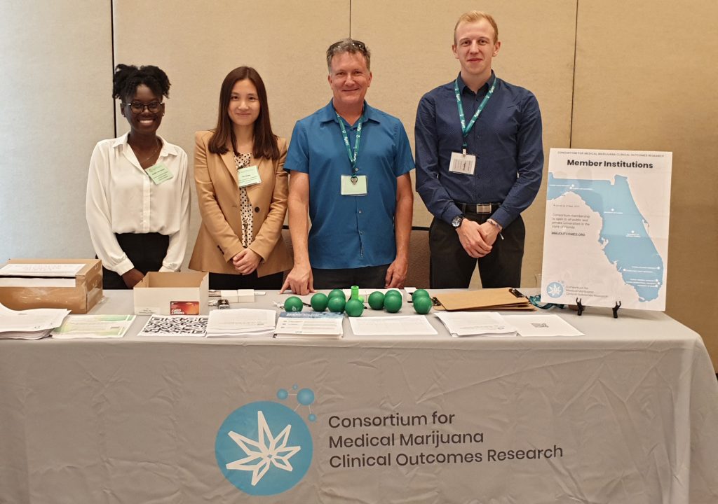 Photo of four Consortium team members at a table with Consortium branded items.